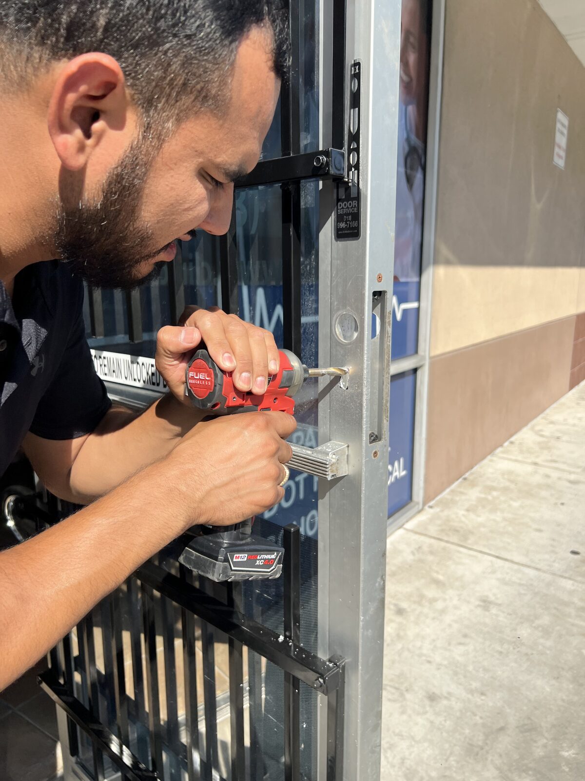 Alamo Key & Lock technician drilling a commercial gate lock during an emergency call