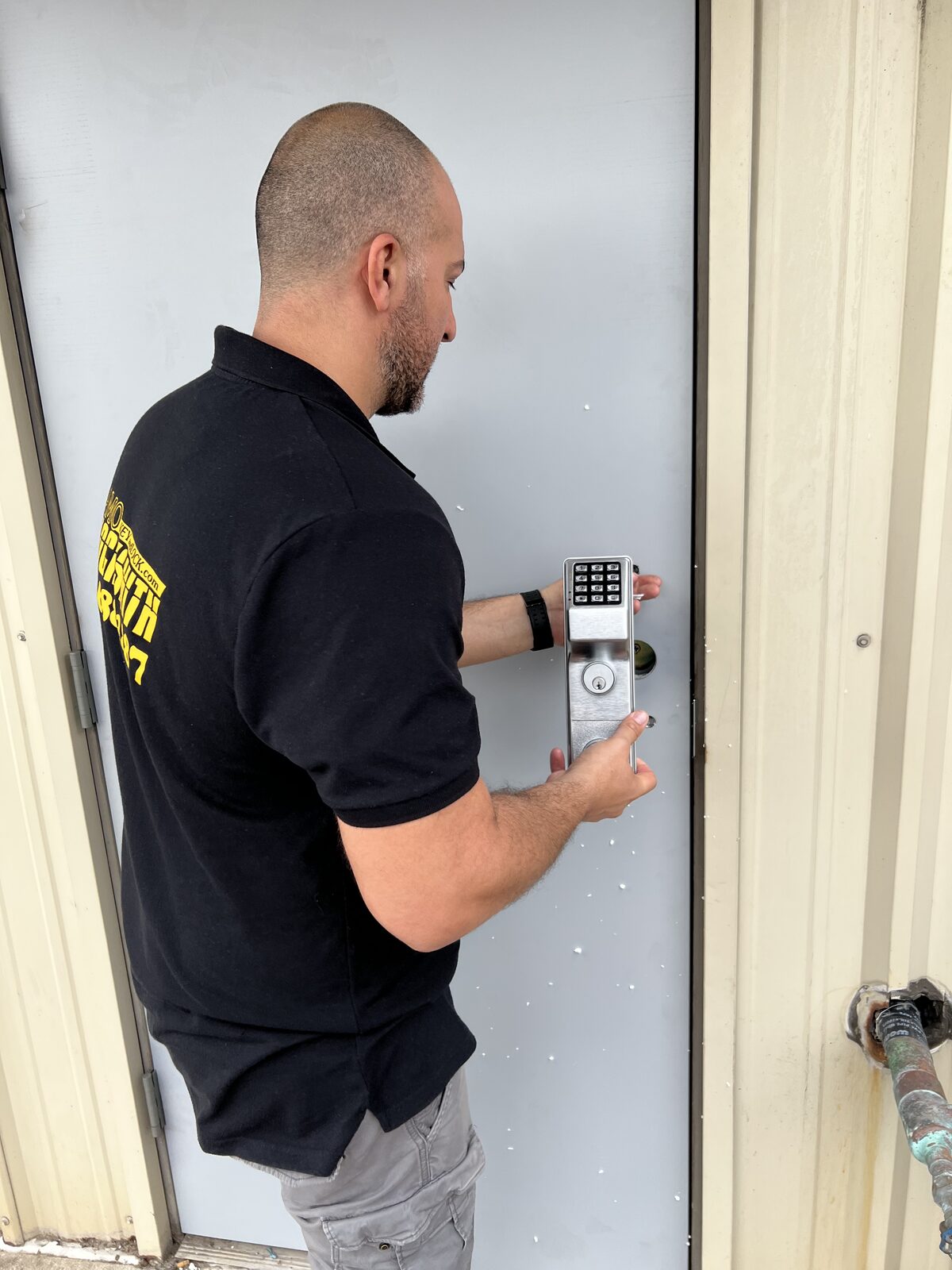 Alamo Key & Lock technician installing a keypad lock on a business door