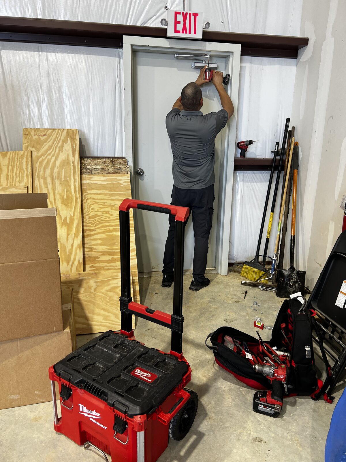 Technician installing a commercial door closer above an exit door