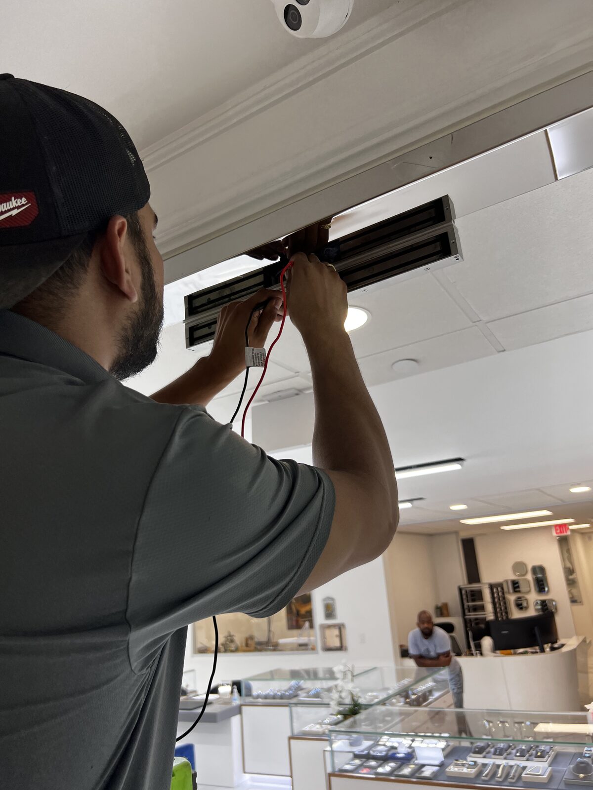 Alamo Key & Lock technician installing a magnetic lock above a commercial door in Houston