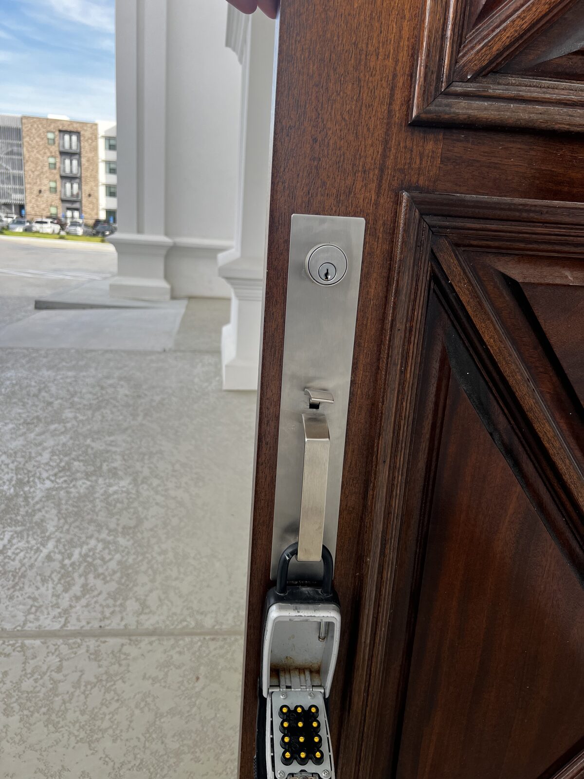 Modern handleset and deadbolt on a new-construction front door with a realtor lockbox