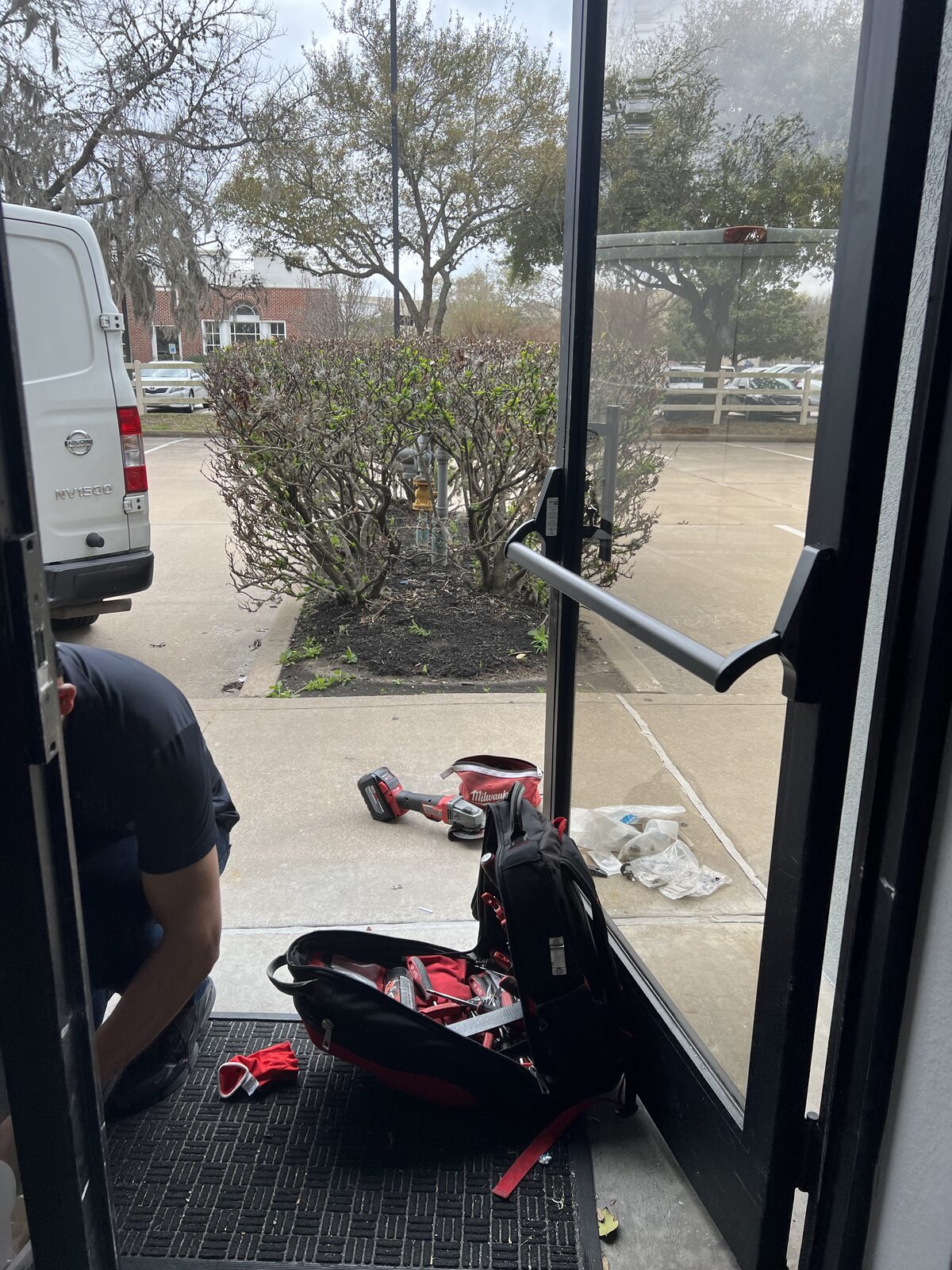 Locksmith repairing a panic bar on a glass storefront door