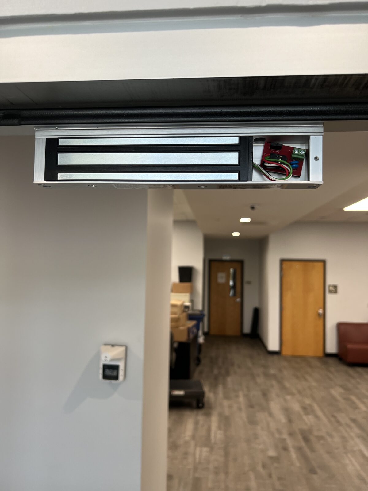 Magnetic lock mounted on the header of an office doorway in Houston