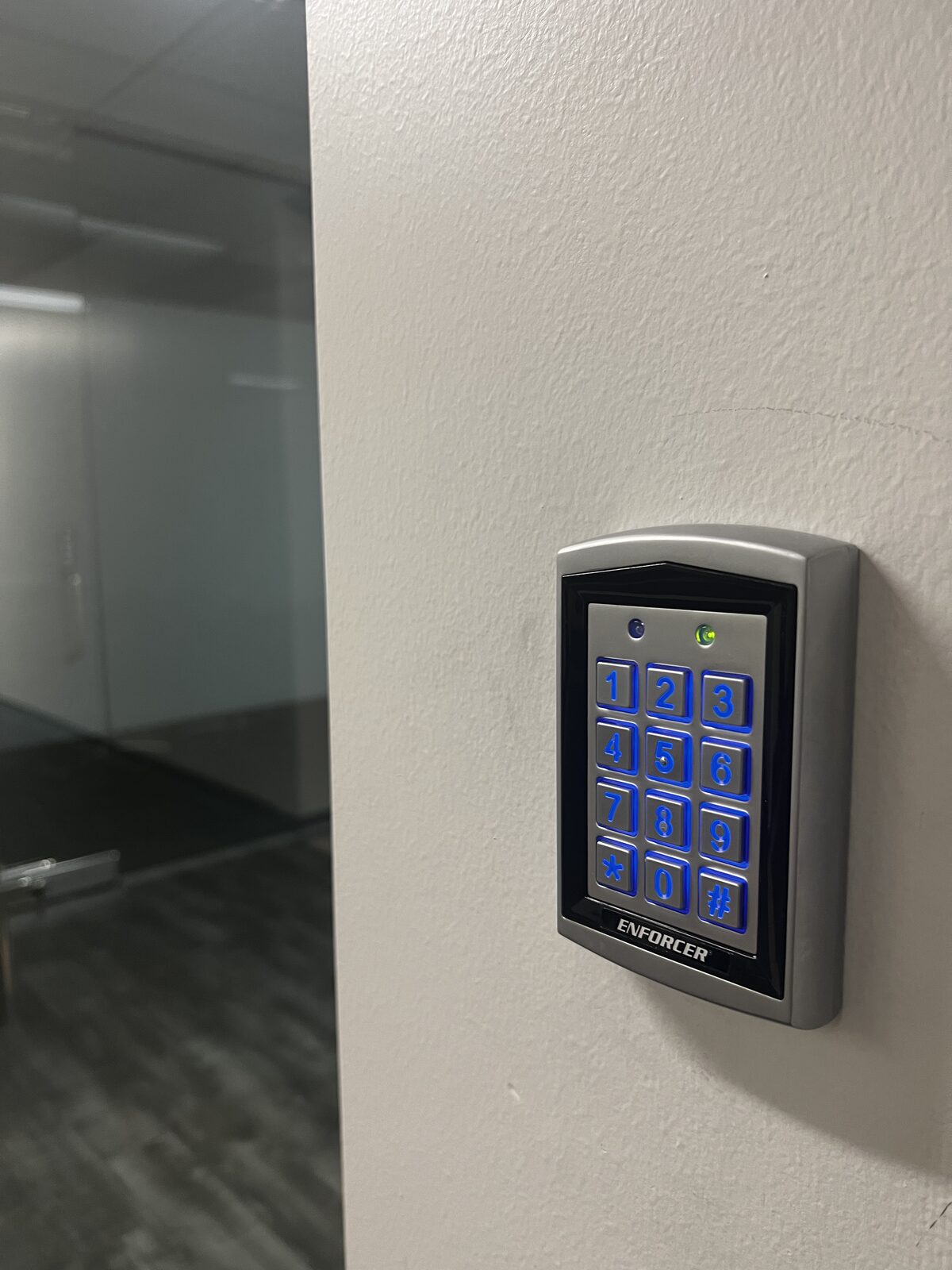 Wall-mounted keypad installed beside a glass office entry door in Houston
